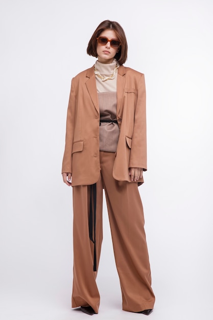 Woman in brown beige suit corset sunglasses jacket pants on white background Bob haircut