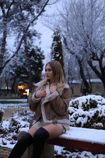 a woman in a brown coat is standing in the snow