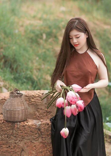 Foto una donna con un vestito marrone sta tenendo un bouquet di fiori