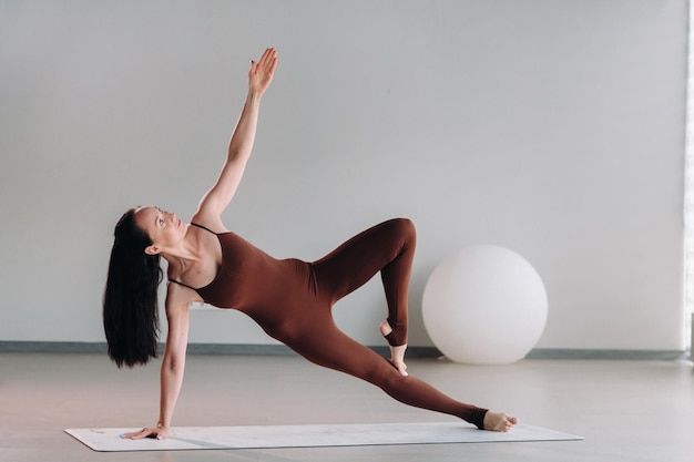 A woman in a brown suit does yoga in a fitness room Healthy lifestyle fitness training selfcare