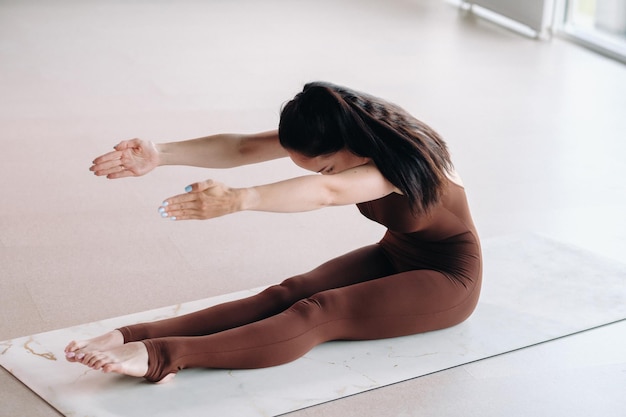 A woman in a brown suit does yoga in a fitness room Healthy lifestyle fitness training selfcare