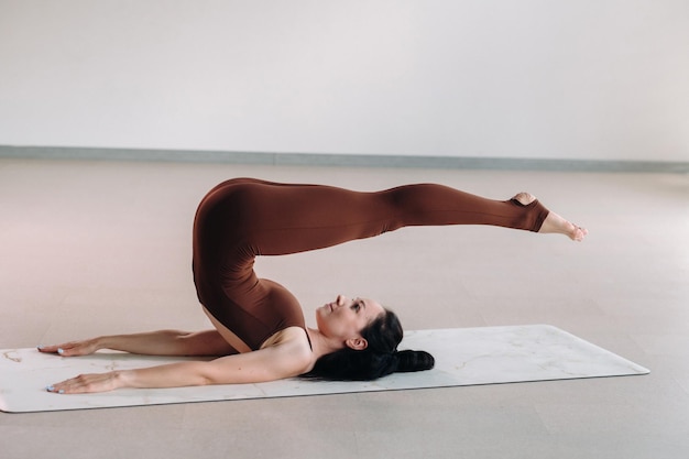 A woman in a brown suit does yoga in a fitness room Healthy lifestyle fitness training selfcare