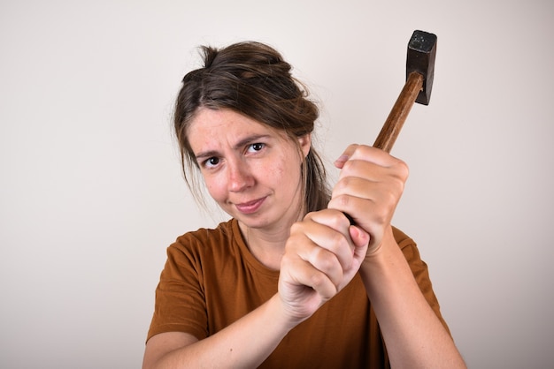 woman in brown T-shirt, holding hammer, isolated. home renovation concept