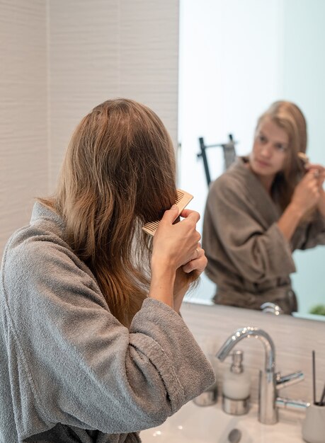 Woman brushing her hair and smiling while looking at the mirror