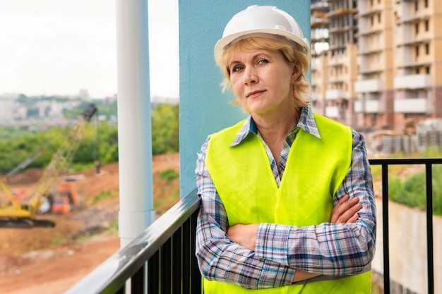 A woman builder at a construction site inspects a building