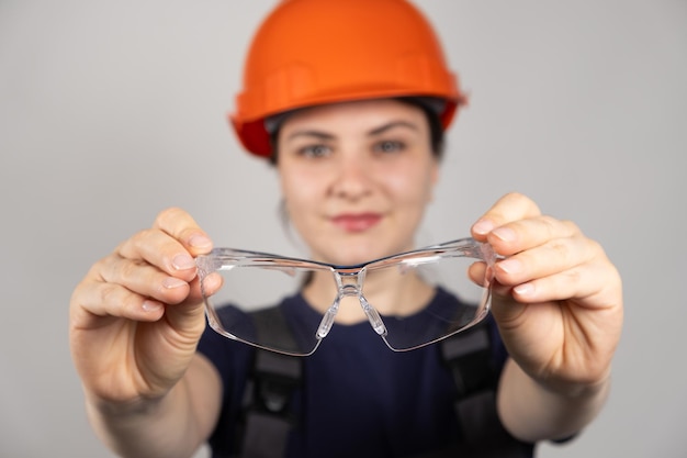 A woman a builder or engineer holds goggles on a white background