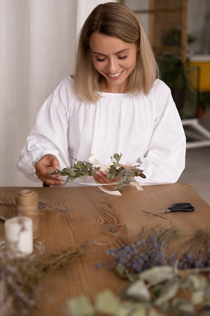 Foto donna che costruisce la propria composizione di fiori secchi