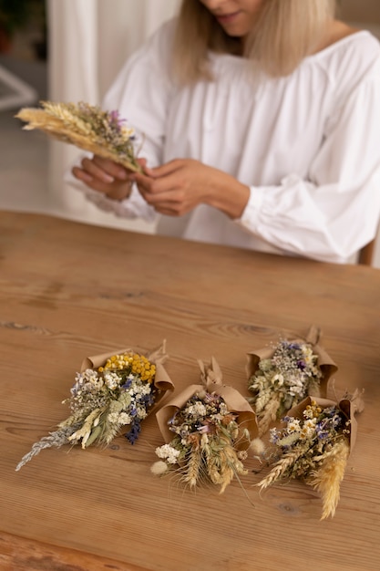 Foto donna che costruisce la propria composizione di fiori secchi