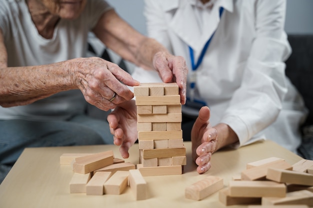 Foto donna costruisce una torre di blocchi di legno con l'aiuto di un medico