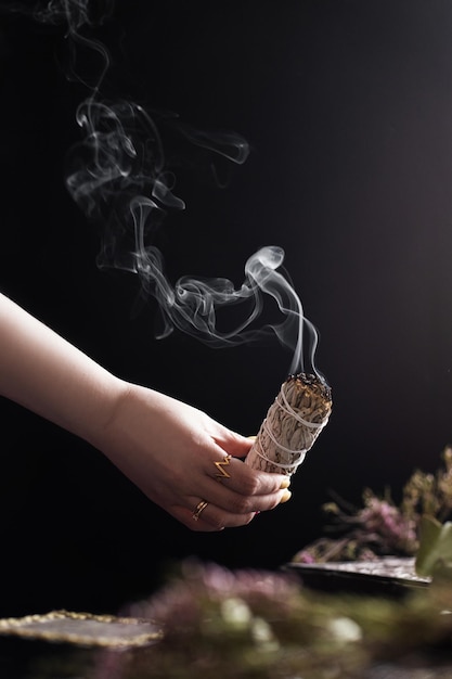 Woman burning sage smudge to cleanse the house