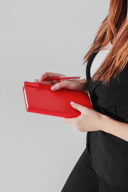 Фото Женщина бизнес-леди в черном костюме с красным ежедневником в руке