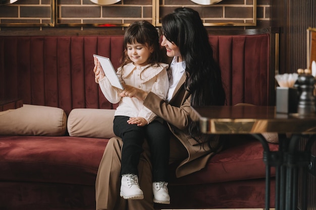 A woman in a business suit holds her child in her arms and speaks via video link on a tablet