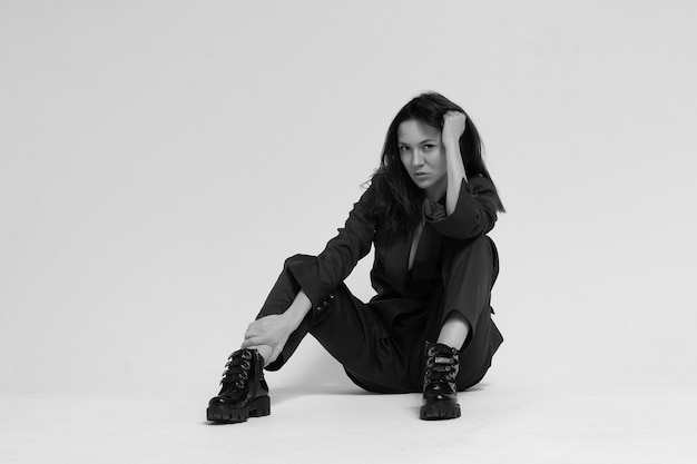 A woman in a business suit sits on white