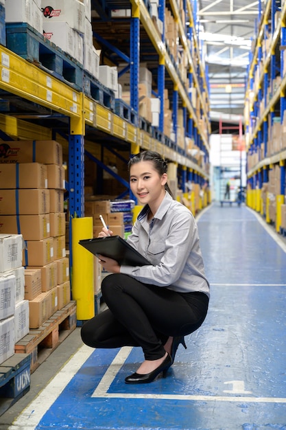 Photo a woman or businesswoman checking and counting the products in the shelf at the big storage and warehouse