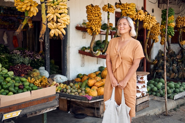 La donna compra frutta fresca al mercato locale esotico