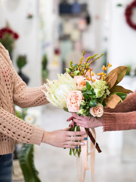 Woman buying a bouquet of peonies and hydrangeas at a flower shop. Small floral business owner. Female power startup concept