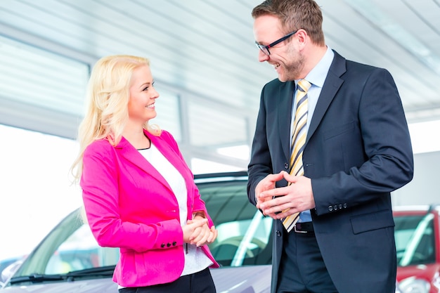 Photo woman buying car at dealership and consulting salesman