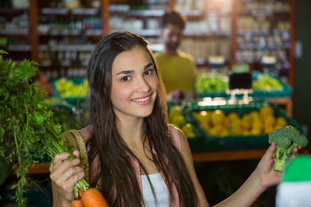 Woman buying carrot and broccoli in supermarket