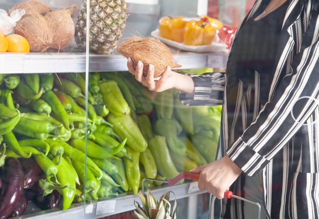 Woman buying coconut at food store.