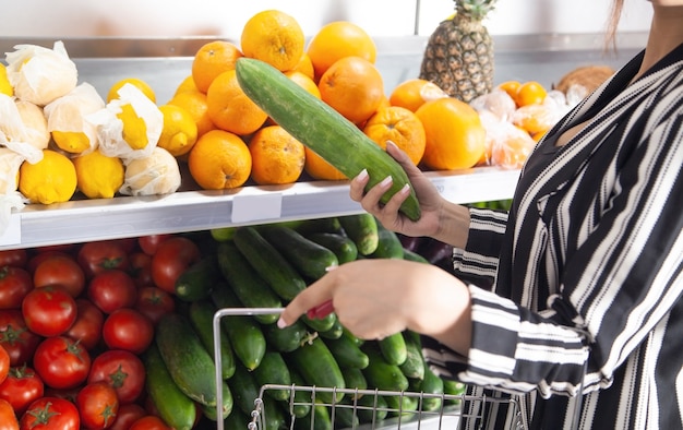 Woman buying cucumber at food store.