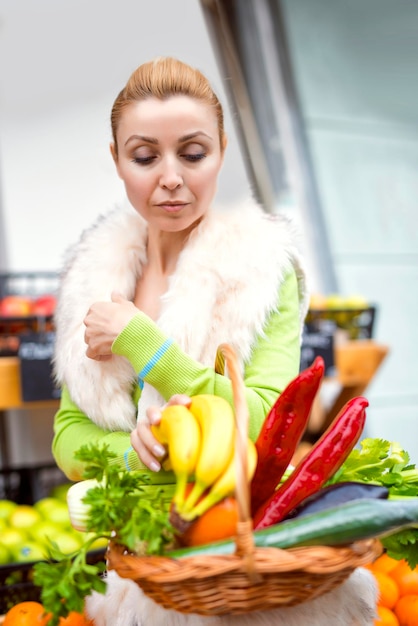 Donna che compra frutta e verdura fresca in un mercato