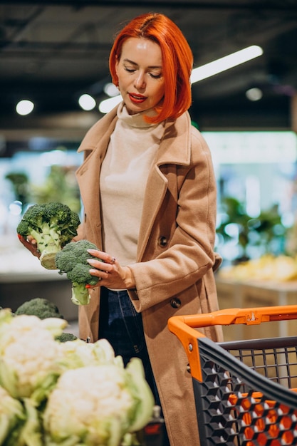 Женщина покупает свежие овощи на супермаркете