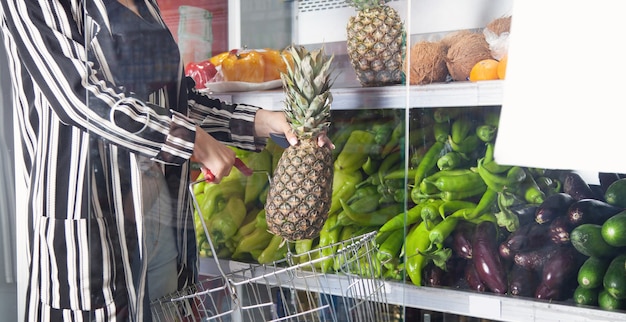 Woman buying pineapple at food store.