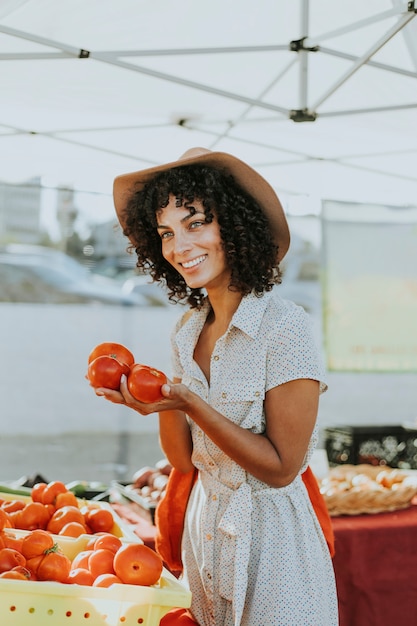 Женщина покупает помидоры на фермерском рынке