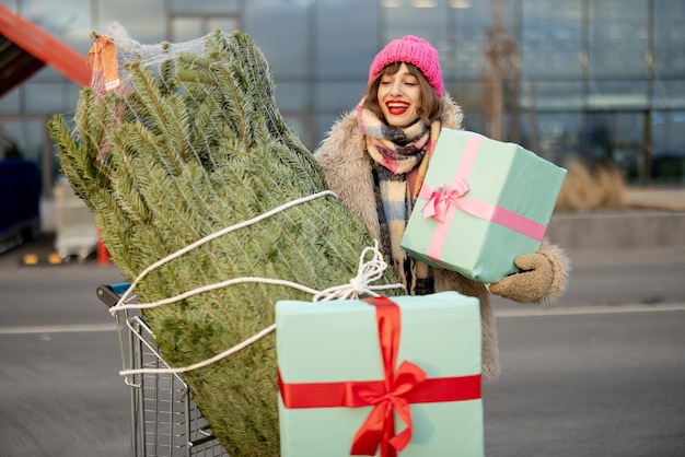 女性はモールでクリスマス ツリーとプレゼントを購入します。