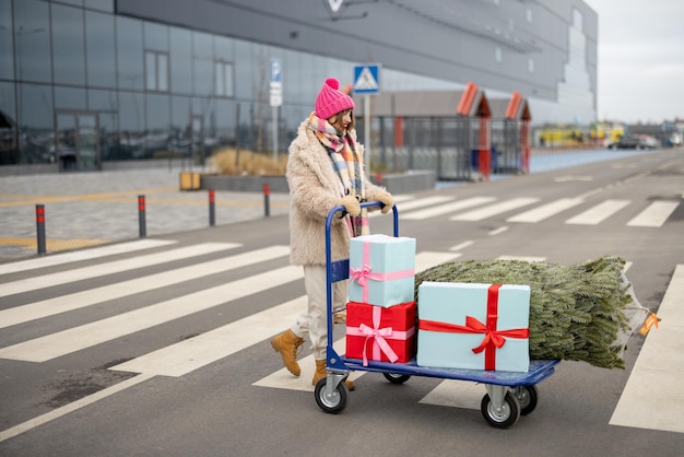 女性はモールでクリスマス ツリーとプレゼントを購入します。