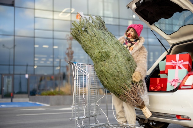 女性はモールでプレゼントとクリスマス ツリーを購入します。