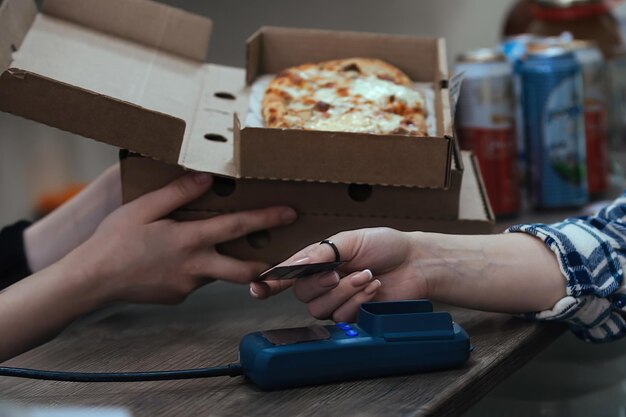 a woman buys readymade food in cardboard boxes and pays with a card through a bank terminal