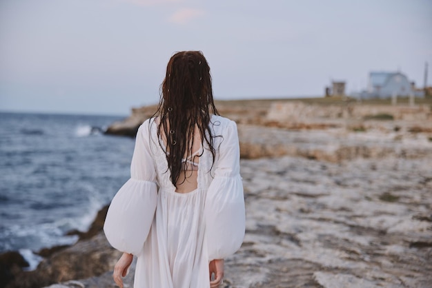 Woman by the ocean stones walk back view