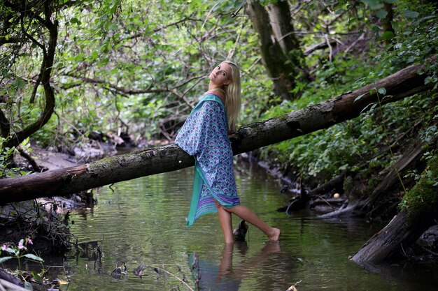 Photo woman by river amidst trees in forest