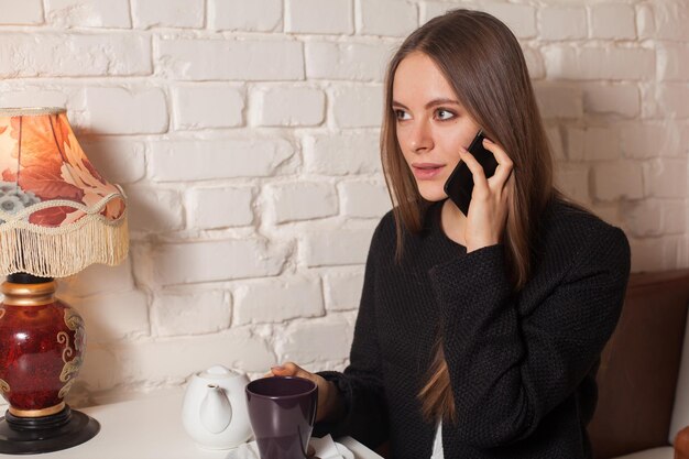 Woman in cafe drinking tea and using her smartphone