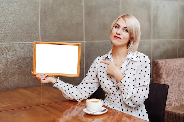 Woman in cafe holding wooden frame