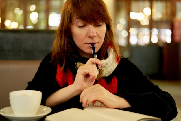 Woman in cafe writes in diary