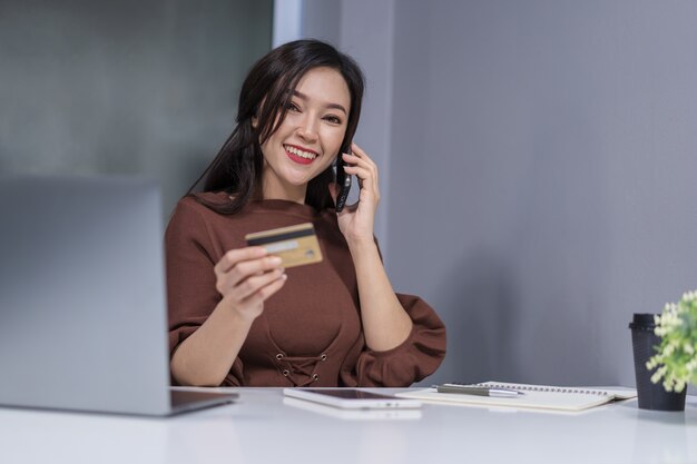 Woman calling by phone and holdind credit card to online shopping 