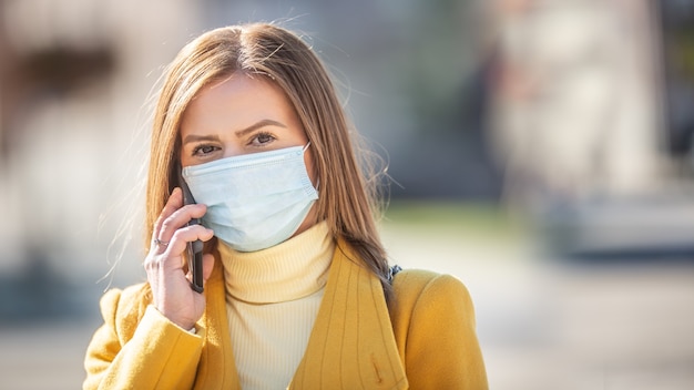 Woman calling on a cell phone wearing a disposable face mask.