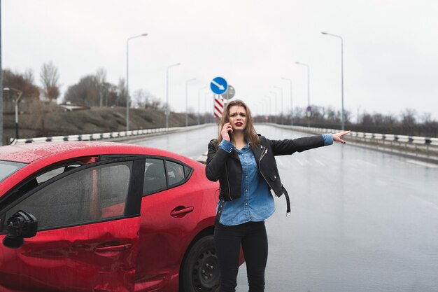 Фото Женщина звонит в службу, стоя у красной машины