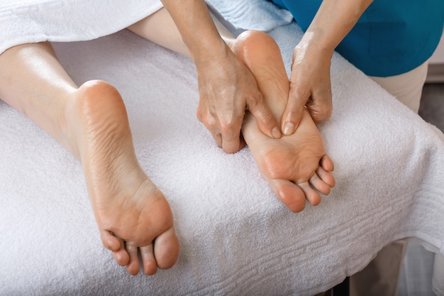 A woman came to a professional for foot massage. Close-up of female legs. Professional masseur doing foot massage