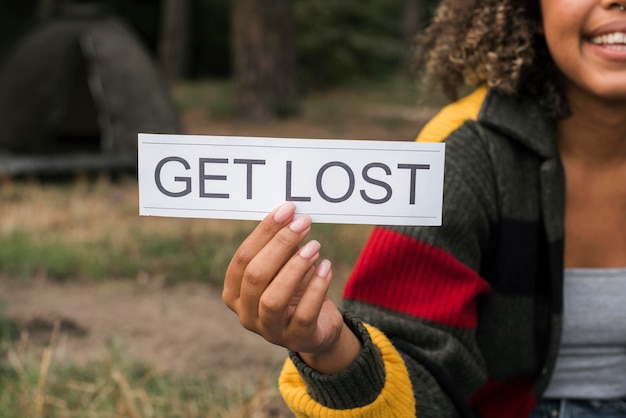 Photo woman camping outdoors and holding get lost sign