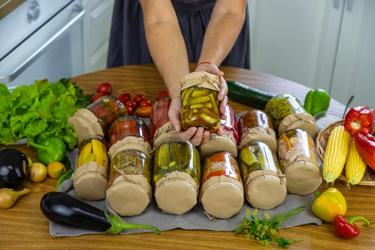 Фотография женщина консервирует овощи в банки на кухне избирательный фокус