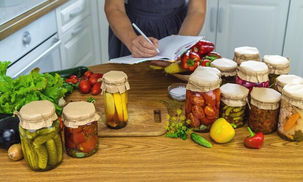 Женщина консервирует овощи в банки на кухне Избирательный фокус