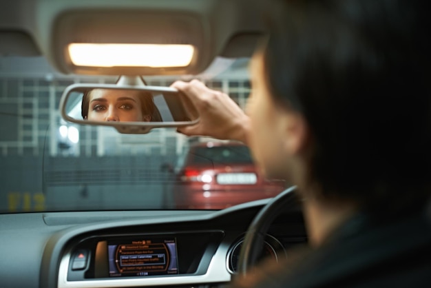 Woman car and checking mirror in parking lot for observation awareness or transportation Female person or driver looking in rear view reflection for drive reverse or interior check in vehicle