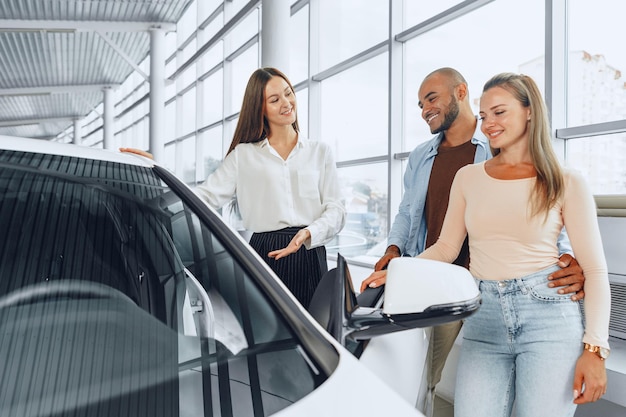 Photo woman car dealer explaining to buyers features of their new car