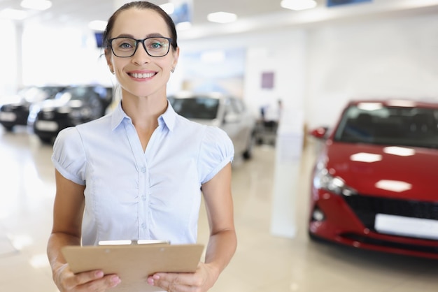 Woman car dealer with clipboard in car showroom sale purchase of new cars in leasing concept