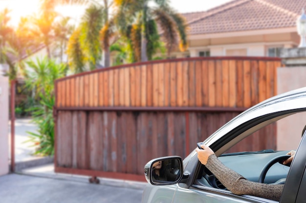 Woman in car hand using remote control to open the home auto door