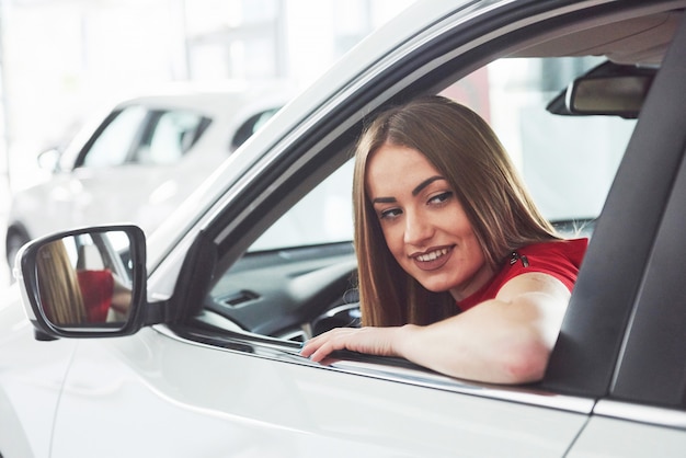 Woman in car indoor keeps wheel turning around smiling looking at passengers in back seat idea taxi driver against sunset rays Light shine sky Concept of exam Vehicle - second home the girl