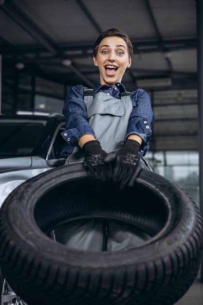 Woman car mechanic changing tires at car service